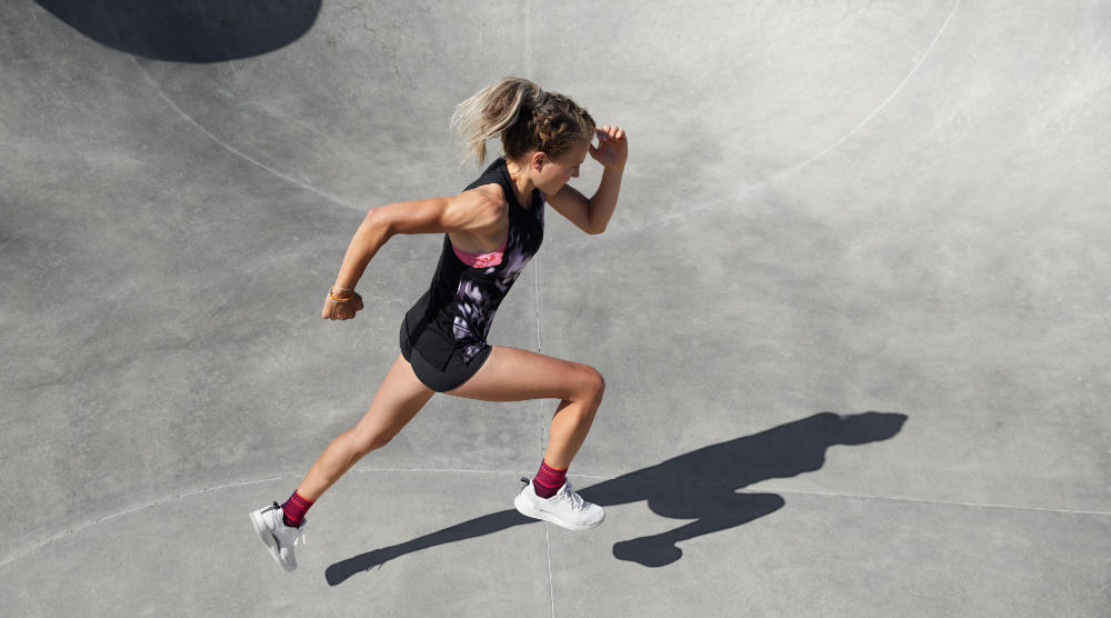 Breaker with ankle bandages in the summer outfit sprints perspective from the side of the concrete surface of the concrete surface