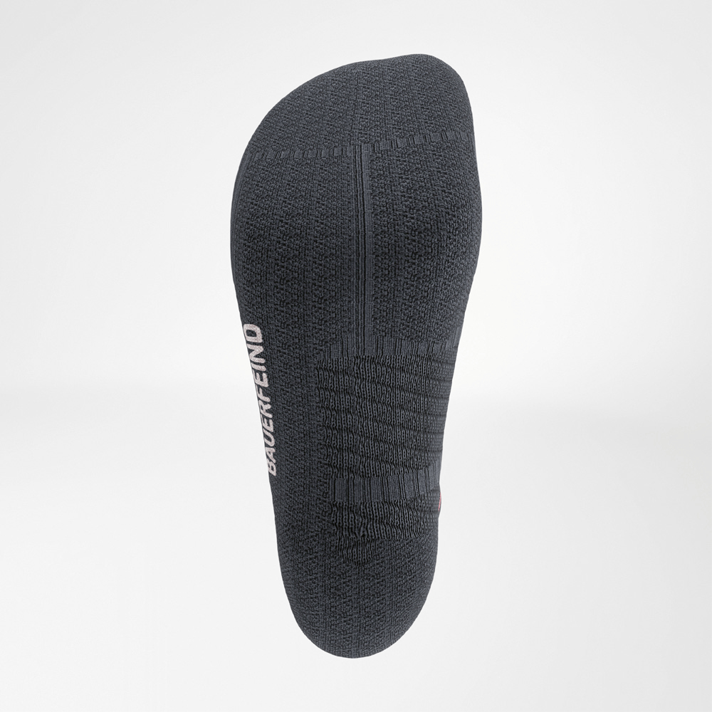 Close-up of the Run Performance Midcut Socks in black with green accents. The image highlights the sole area with its supportive knit structure designed for running comfort. The Bauerfeind logo is integrated on the side.