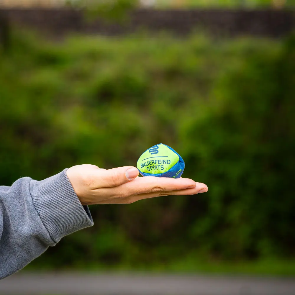 Hand holding a small Bauerfeind Sports ball, ideal for training and coordination.