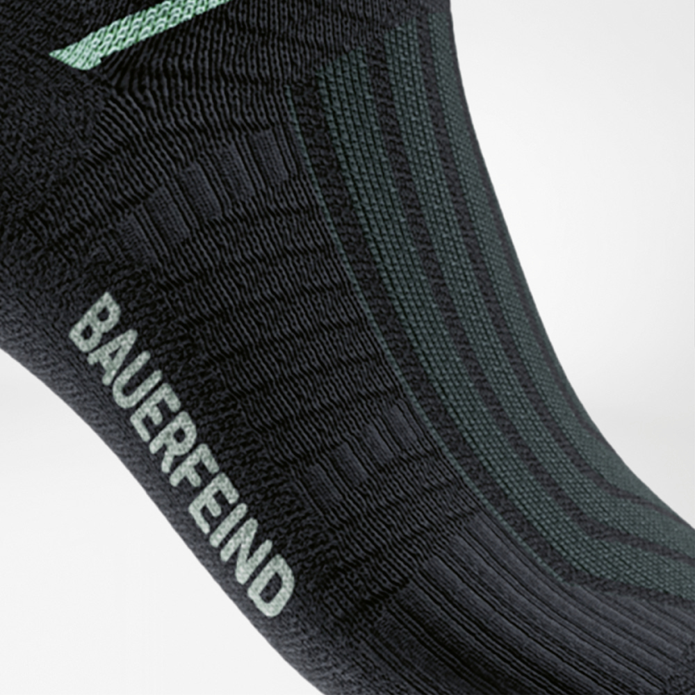 Close-up of the Run Performance Midcut Socks in black with a mint-colored arch lift element. The view highlights the special compression zone at the arch, providing stability and secure support.