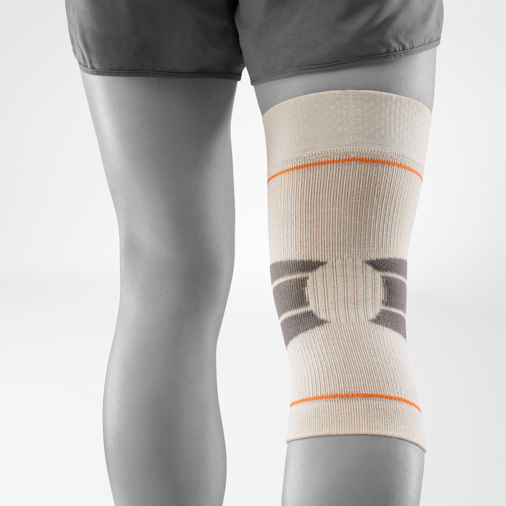 Close-up of the sand-colored knee support in outdoor use. The breathable knit with reinforcement zones provides stability and freedom of movement, ideal for hiking, running, or other outdoor sports.