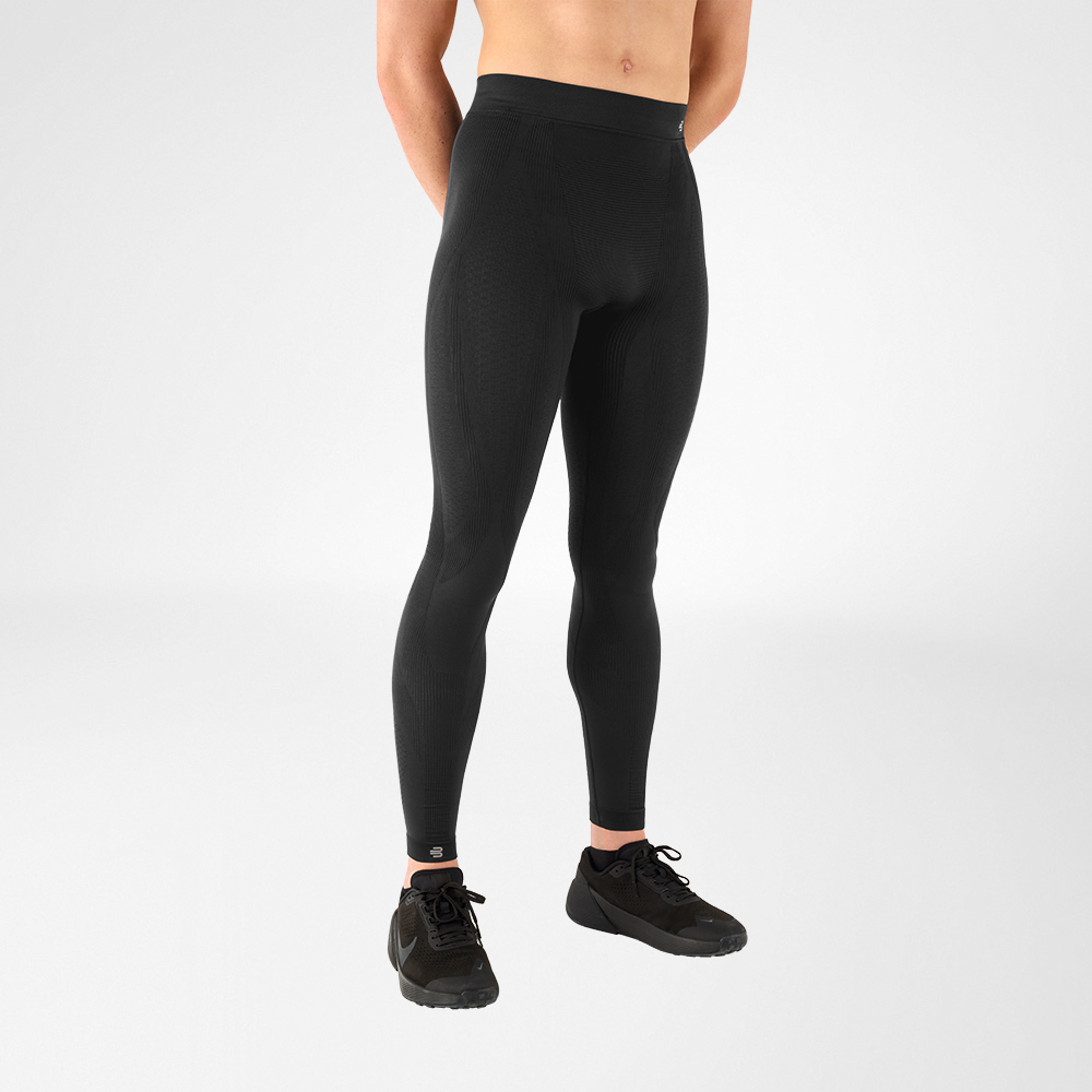 Zu sehen ist ein Mann von Rumpf bis Fuß, der eine anthrazitfarbene Sporthose trägt sowie schwarze Turnschuhe