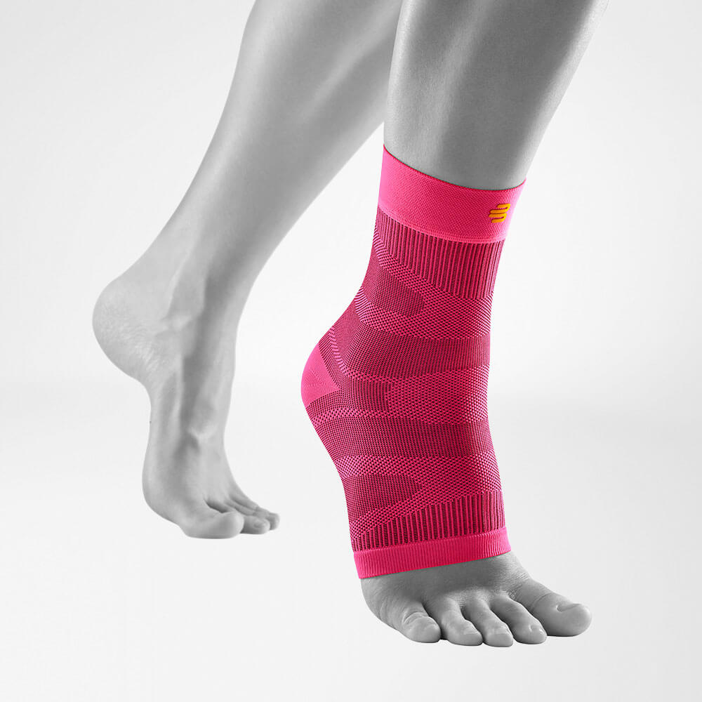 Compression Ankle Support Pink front view diagonally Complete view of the pink compression ankle support on a stylized gray leg