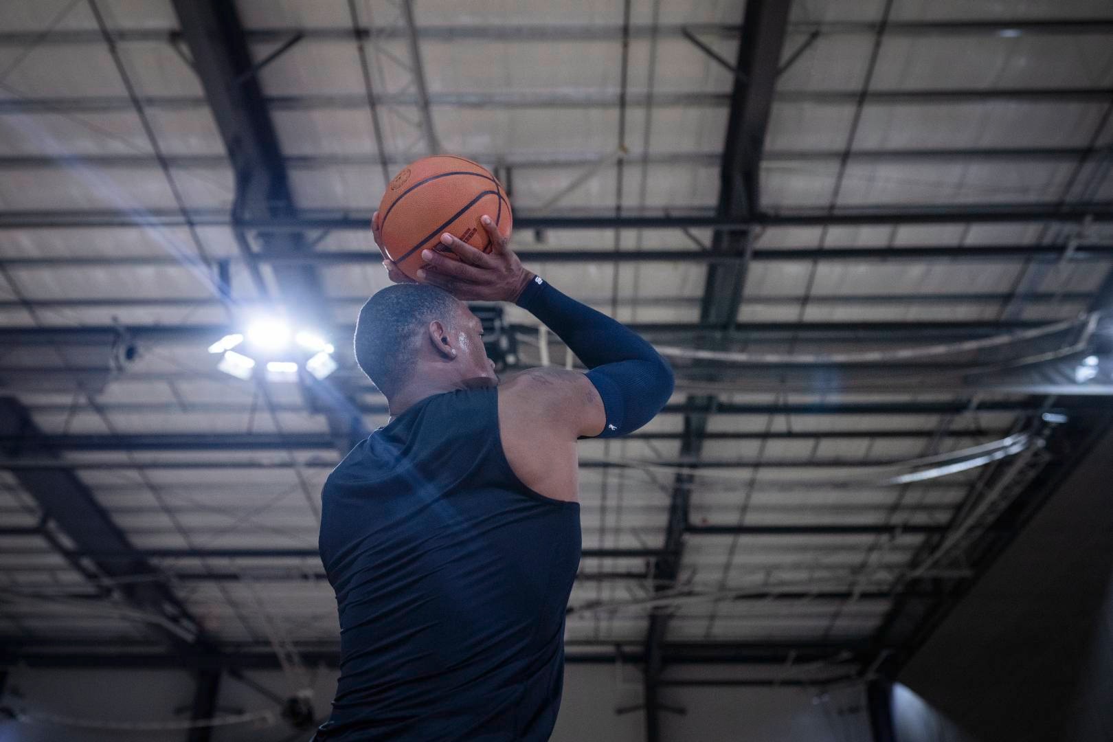 Basketball players with a blue armsleeve in a sports hall starts with their hands above the head to the throw