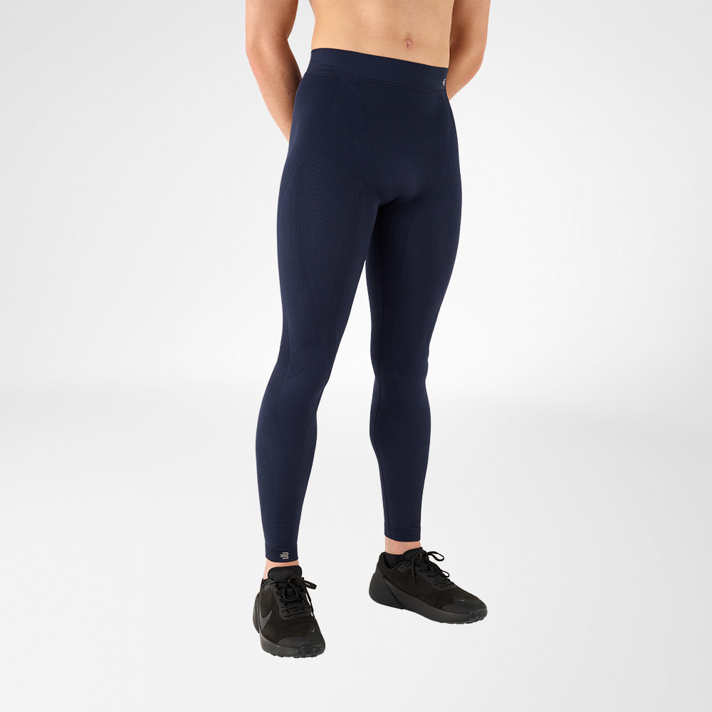 Zu sehen ist ein Mann von Rumpf bis Fuß, der eine anthrazitfarbene Sporthose trägt sowie schwarze Turnschuhe