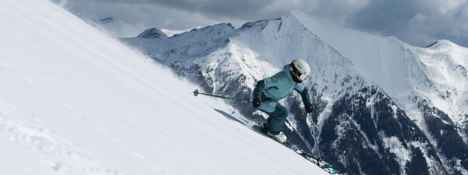 Skiers drives down a post, there are snow -covered mountains in the background