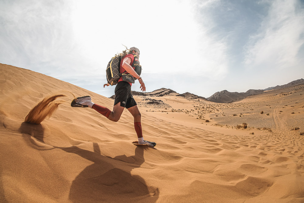 Ultra runner crossing sand dunes in a remote desert landscape