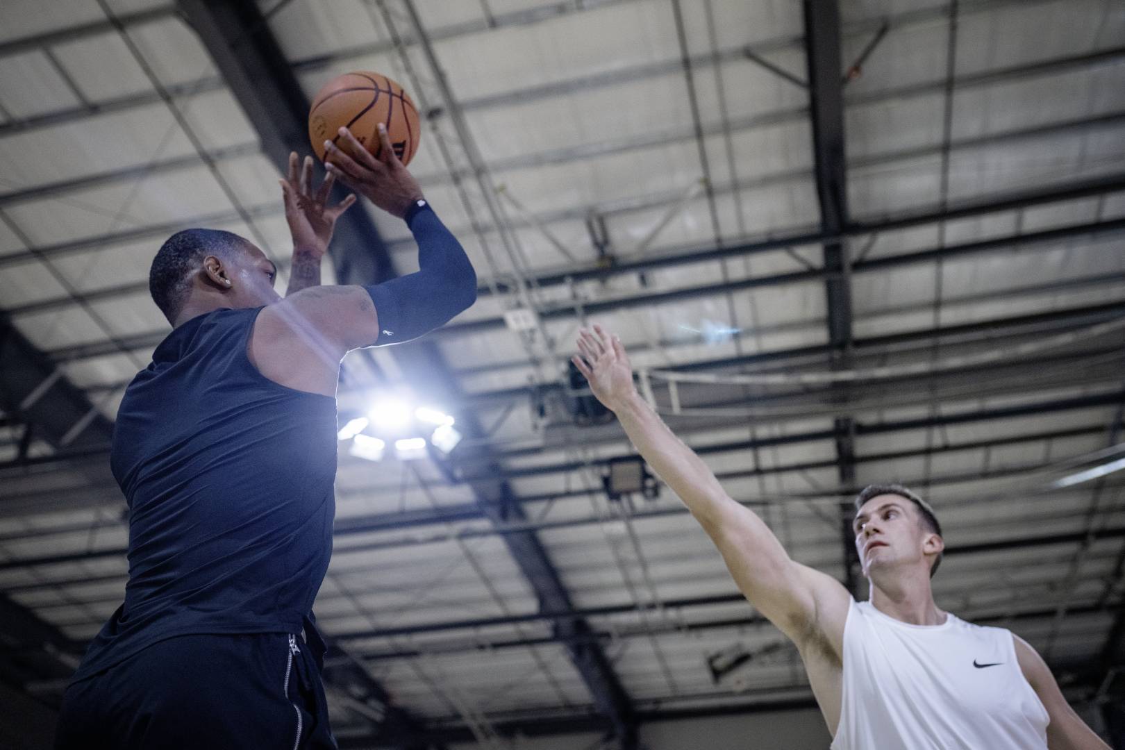Basketball players with a blue armsleeve in sports hall tries to throw over the outstretched arm of an opposite