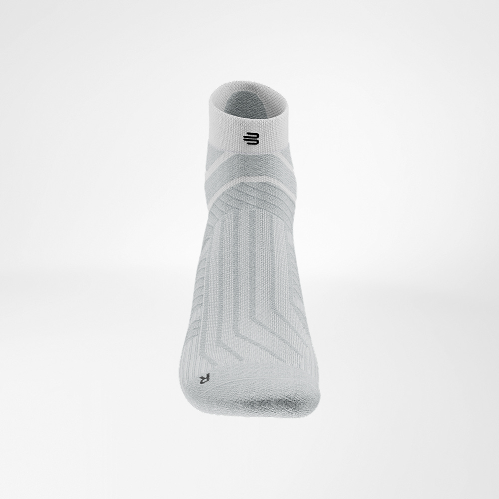 Fresh momentum in white White Run Performance Low Cut Sock from Bauerfeind, close-up of the instep with breathable knit design and black logo on the cuff.