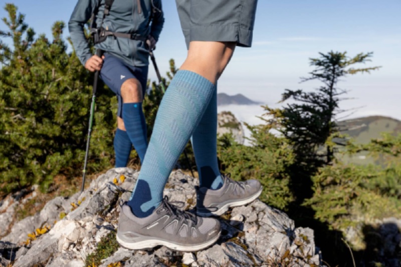 Two hikers wearing Outdoor Merino Compression Socks on a rocky trail. These compression socks provide optimal comfort and support for long hikes in a natural environment.