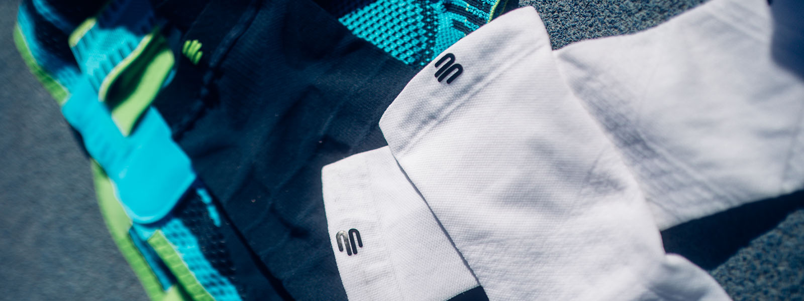 Close-up of various Bauerfeind Sports products, including compression garments in different colors. The featured textiles display the brand's iconic logo.