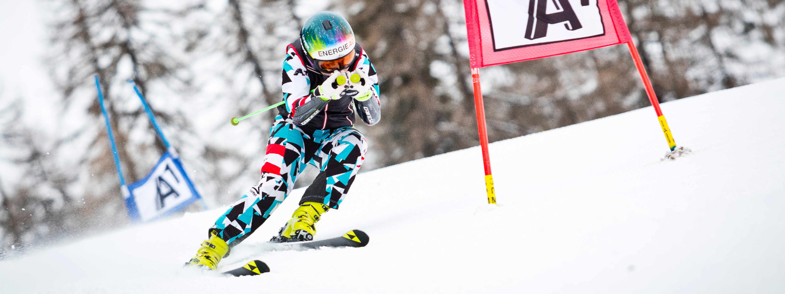 The giant slalom combines demanding turns with the acceleration of a descent Ski runner in a blue and white-red racing suit goes into the departure position after passing a large goal