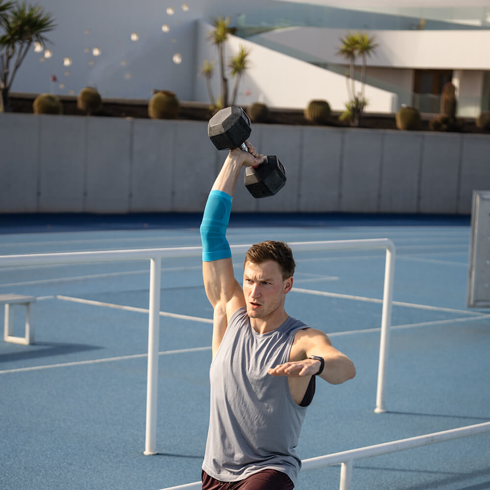 Ellenbogenensleeve during training Man trains with a dumbbell and wears a sports leeve for the elbow