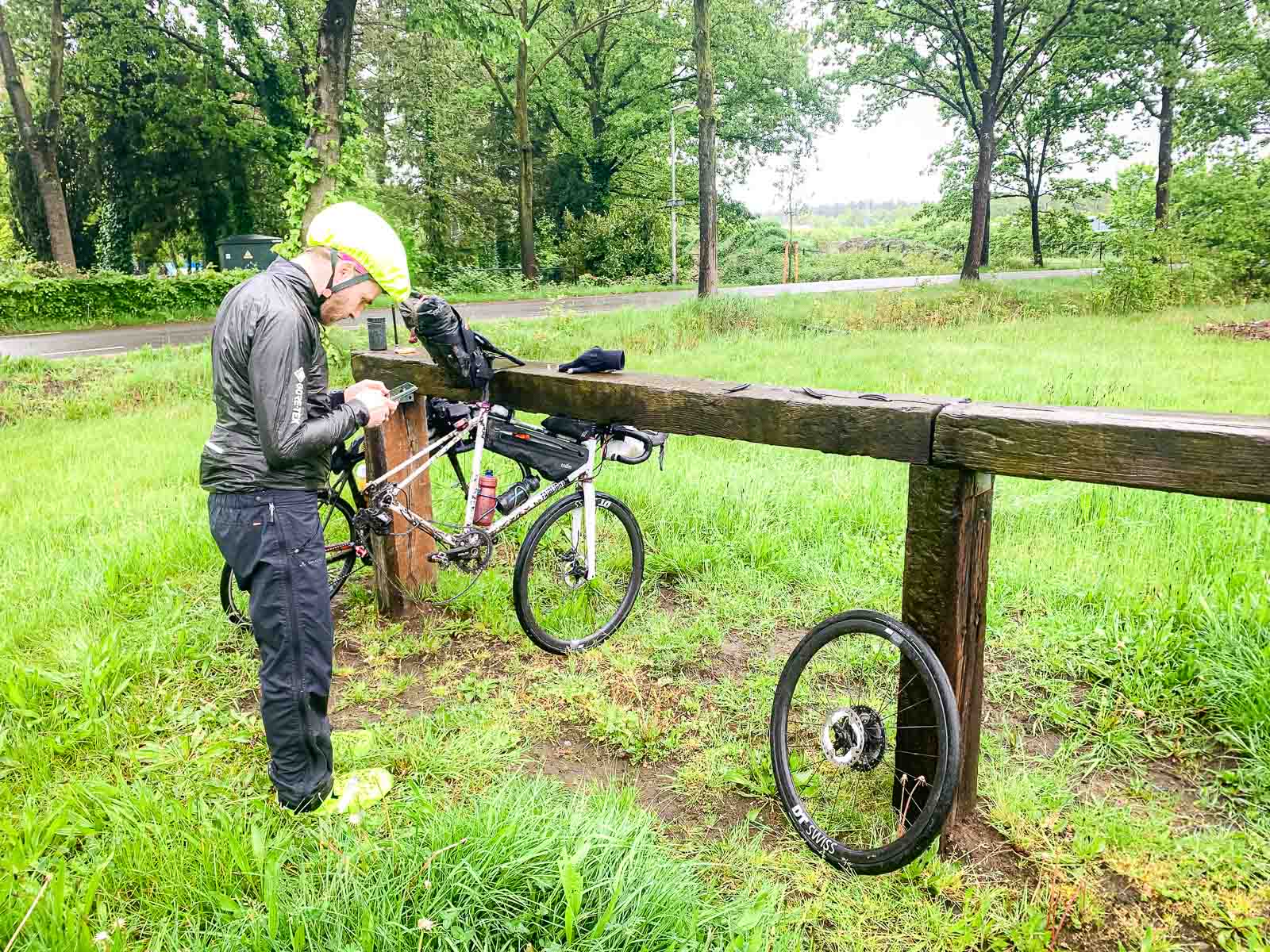 A bicycle with a flat tire is hung over a wooden parapet.