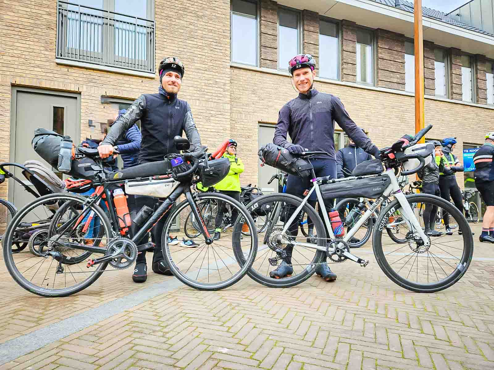 Two participants in the utra cycling event Race around the Netherlands stand at the start and laugh into the camera