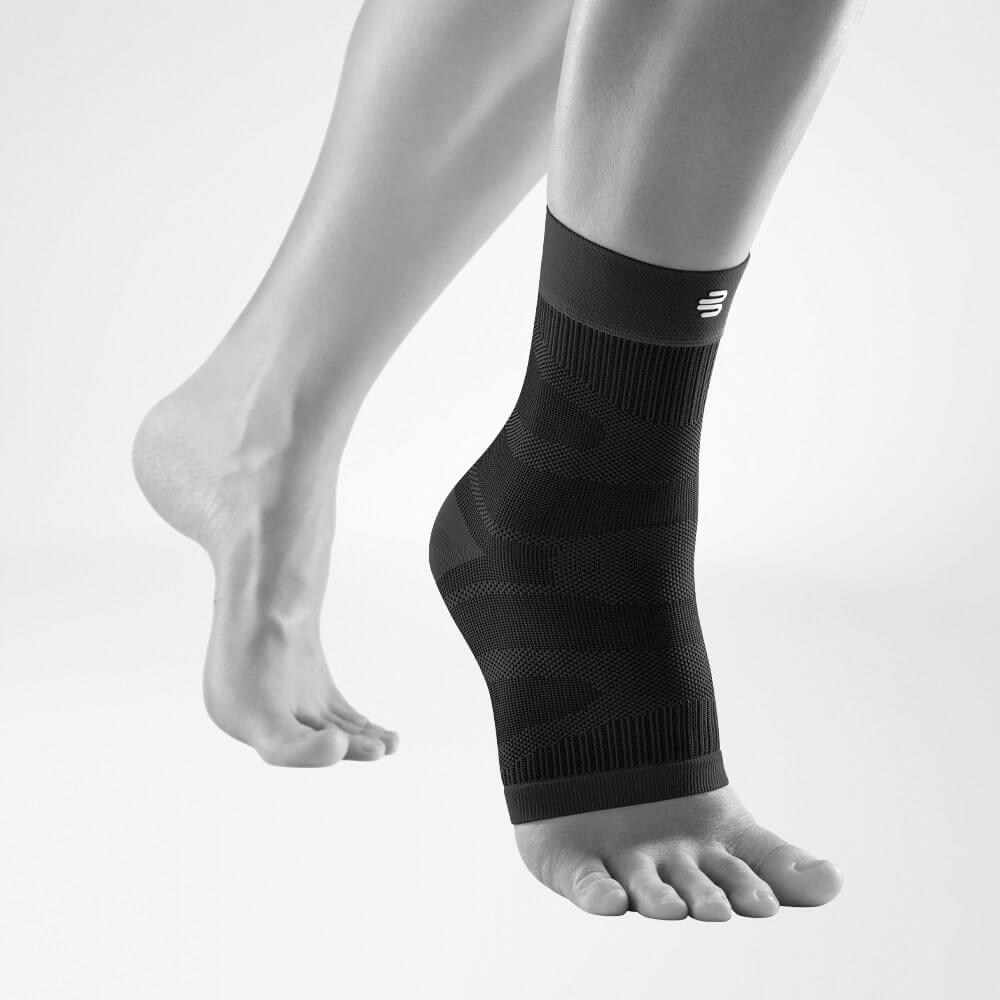 Compression Ankle Support Black front view diagonally Complete view of the black compression ankle support on a stylized gray leg