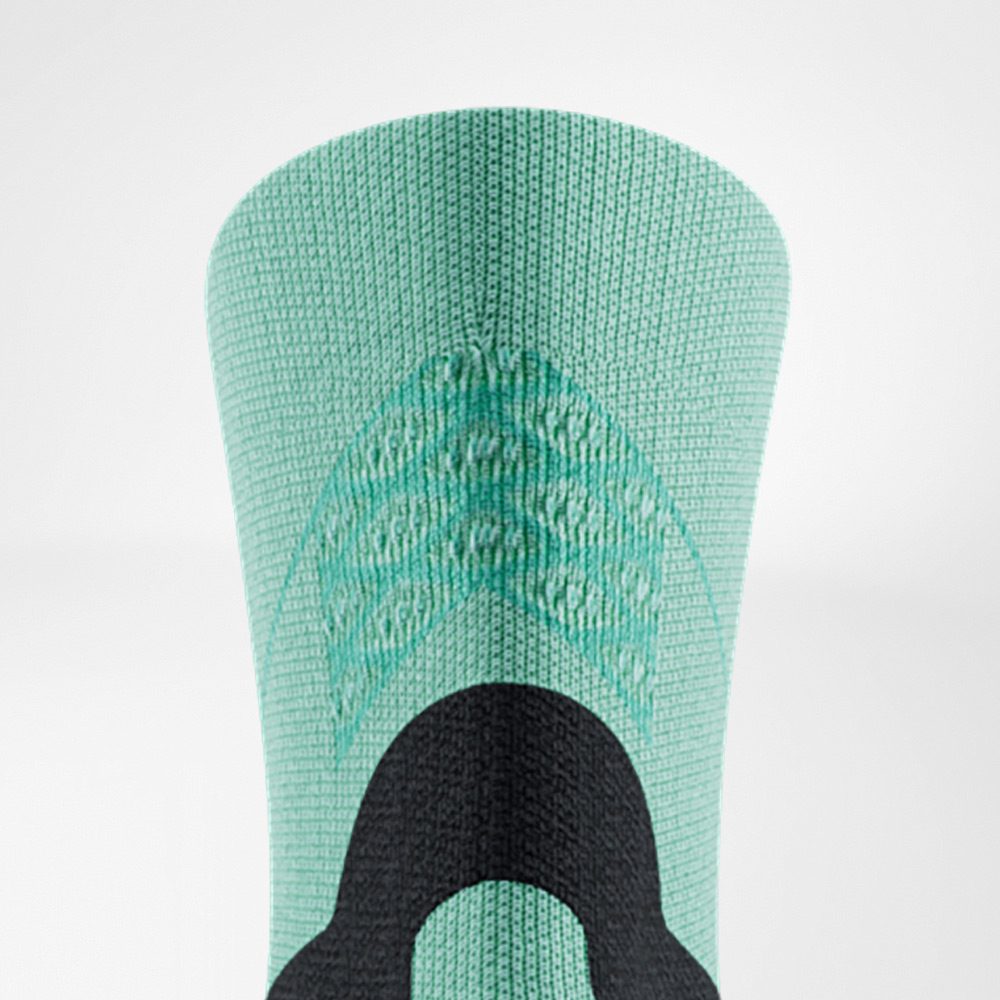 Close-up of the shaft of a green Run Performance Midcut Sock by Bauerfeind. The woven structures in the upper section and a black reinforcement element for support and stability are clearly visible.