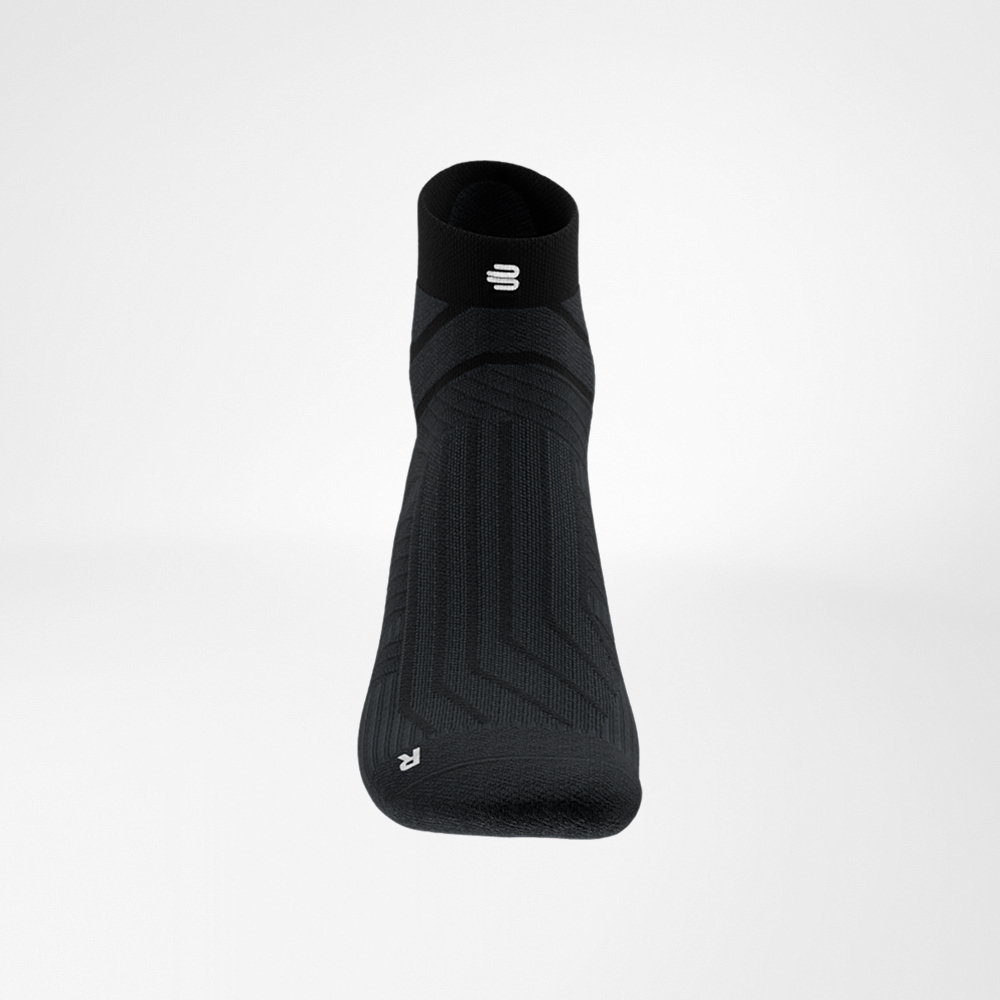 Close-up of the cuff of the black Run Performance Low Cut Sock by Bauerfeind, featuring the white B-logo and fine ribbed structure.