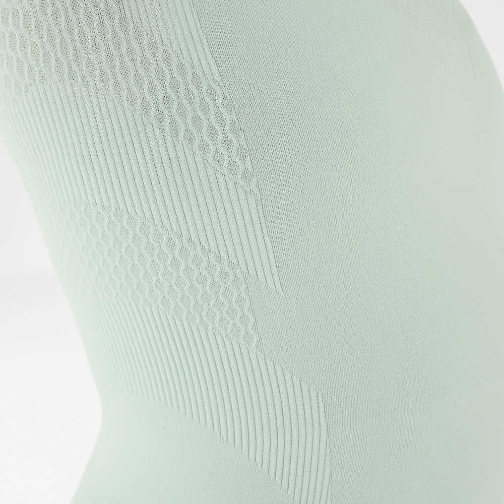 Close-up view of a light green, close-fitting long sleeve shirt with textured design