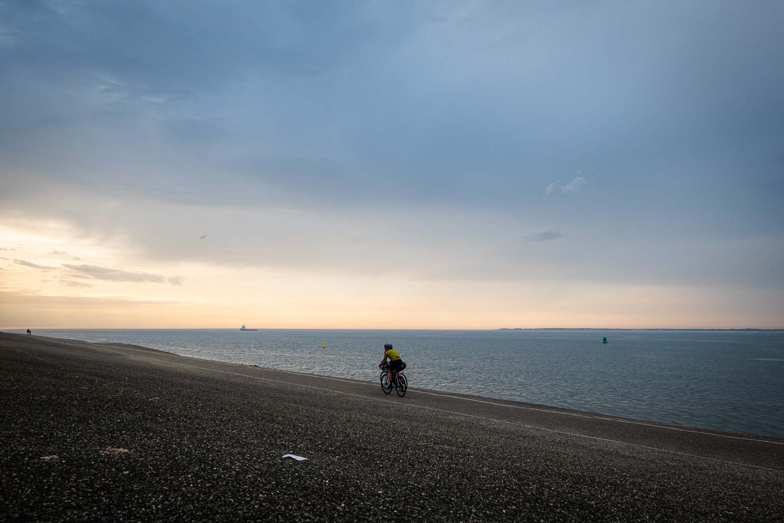 Two participants in the Race around the Netherlands ride their bikes towards the evening sun.
