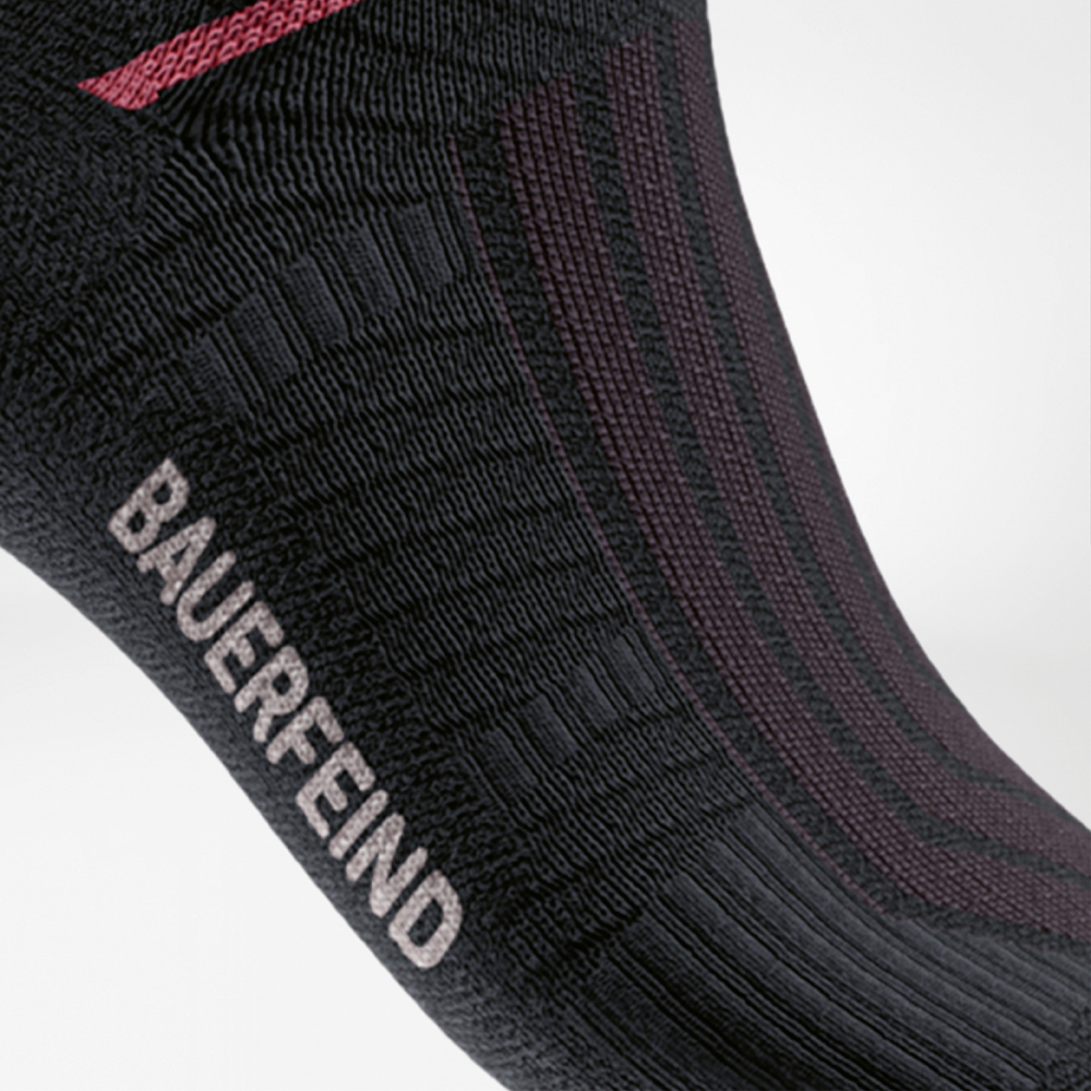 Close-up of the Run Performance Midcut Socks in black with a red arch lift element. The image emphasizes the reinforced compression zone at the arch for optimal stability and secure support.