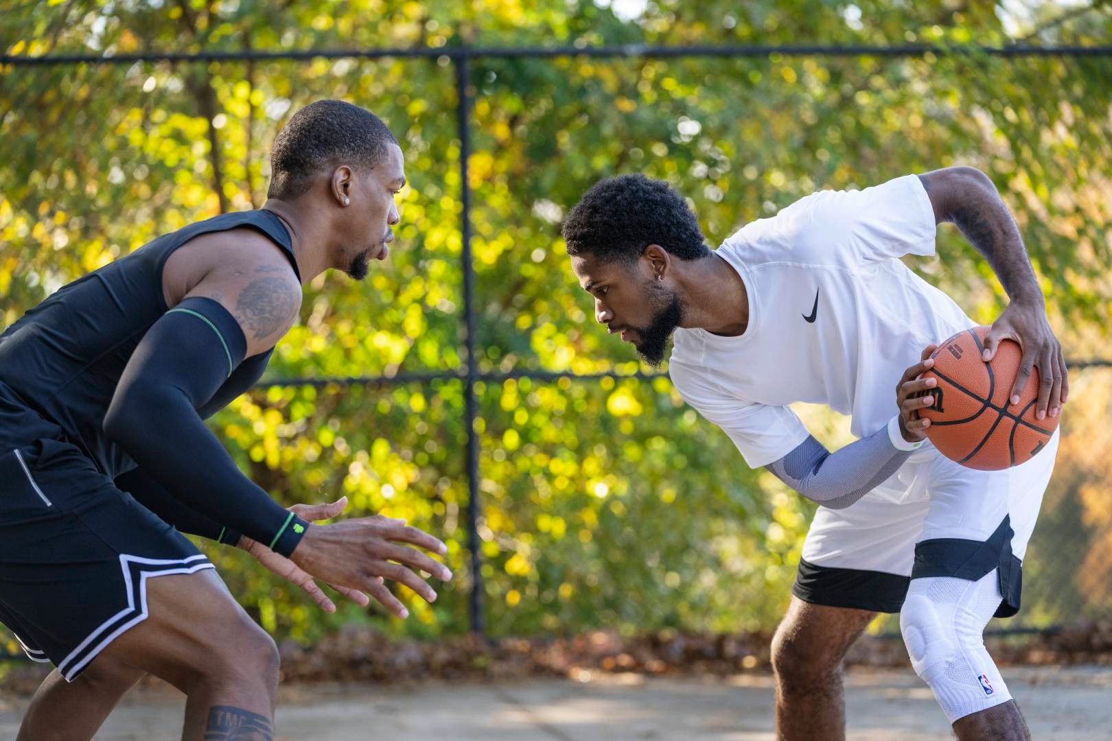 Streetball player in white game clothes tries to play his opponent in black game clothes