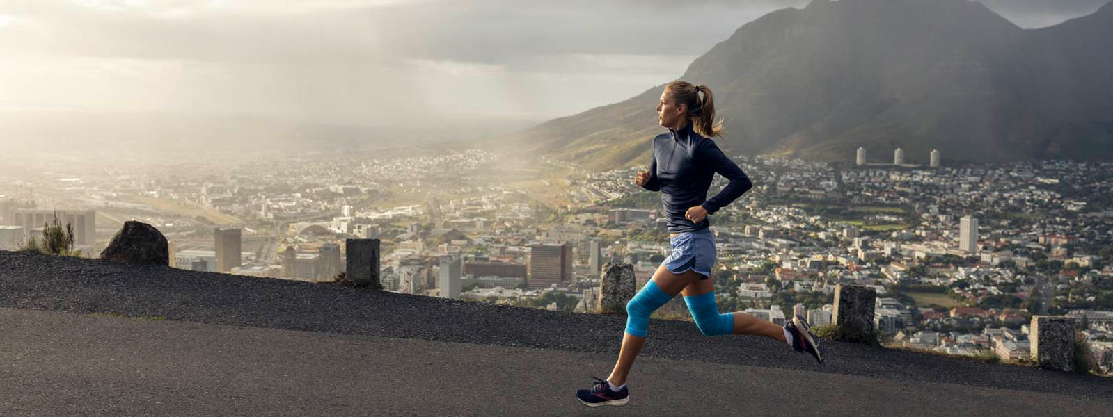 Woman runs on the mountains over the city in summer