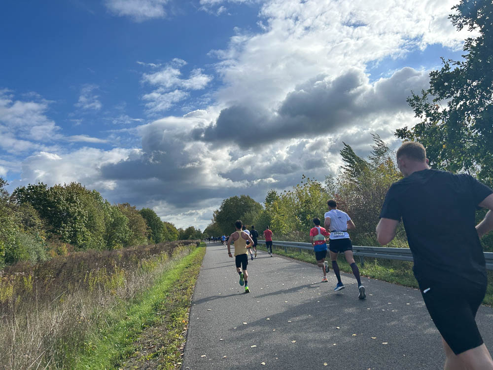 Runners competing in a half marathon on a paved course in sunny autumn weather
