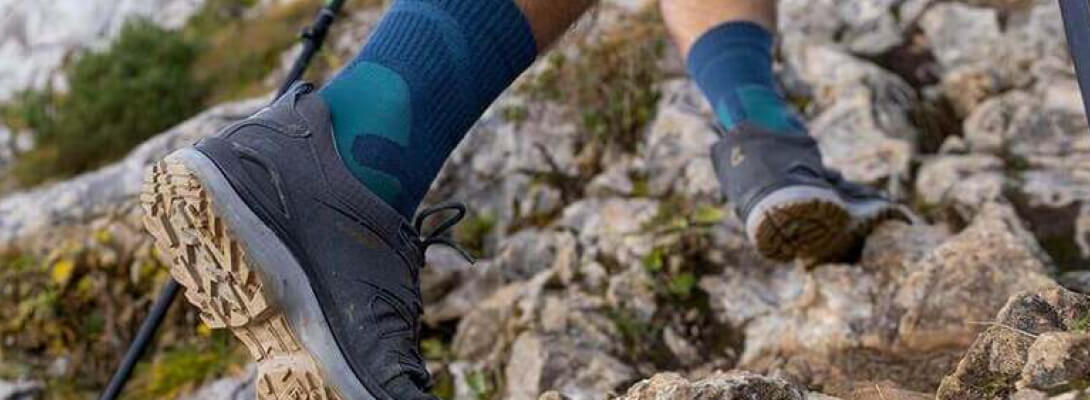 Medo-length merino hiking socks while climbing Person goes up a mountain over stones and wears medium -length hiking socks