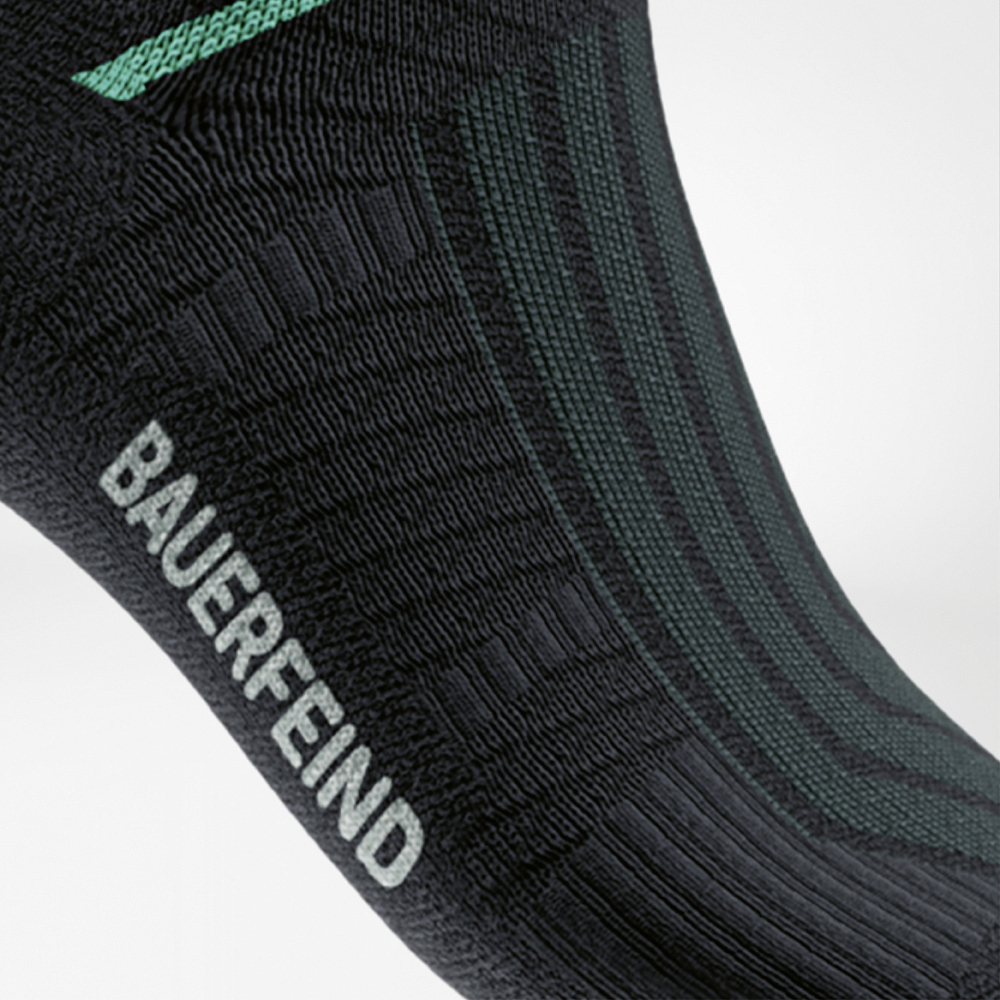 Close-up of the Run Performance Midcut Socks in black with a green arch lift element. The detailed view highlights the structured compression zone at the arch, providing targeted stability and support.