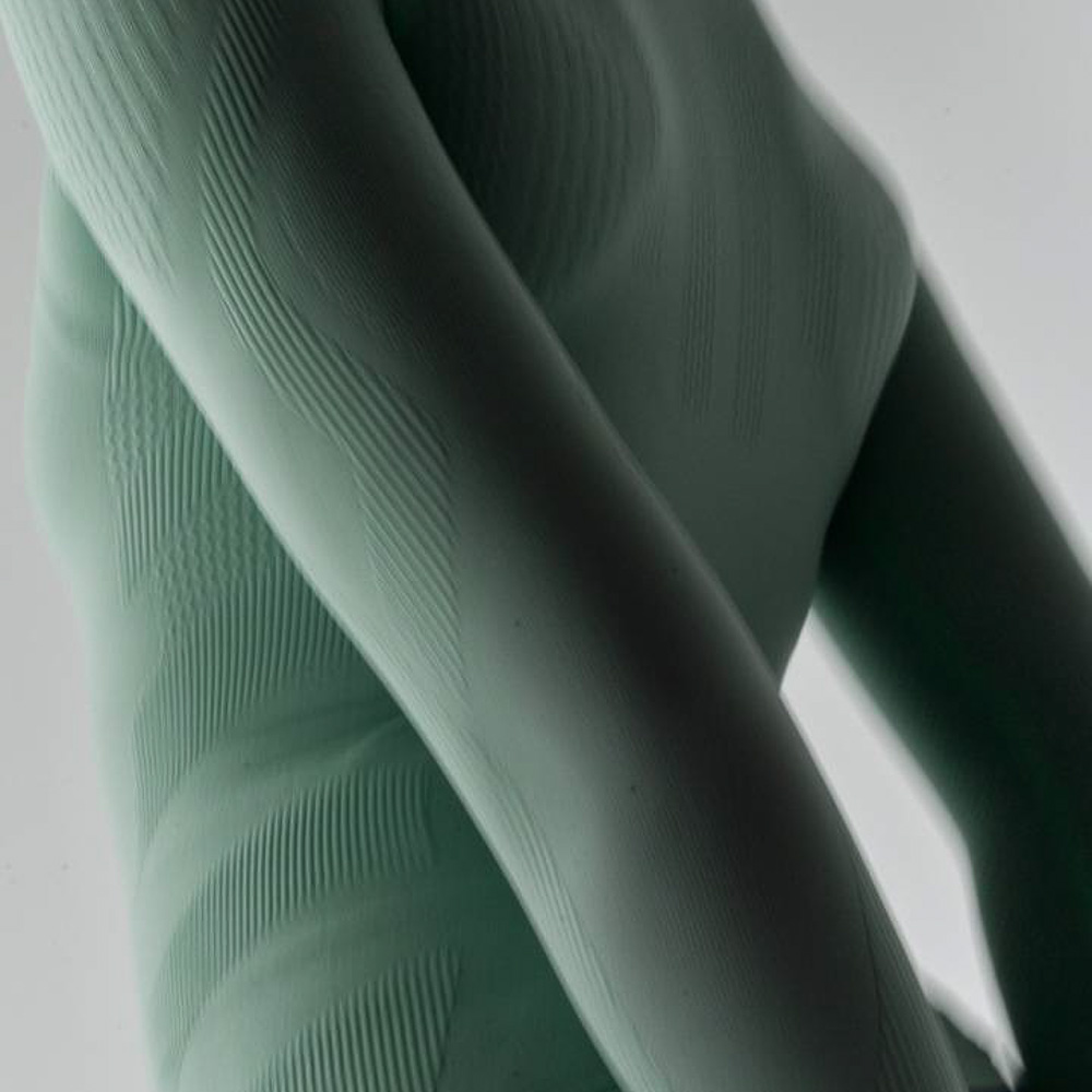 Upper body of a woman wearing a light green sports top