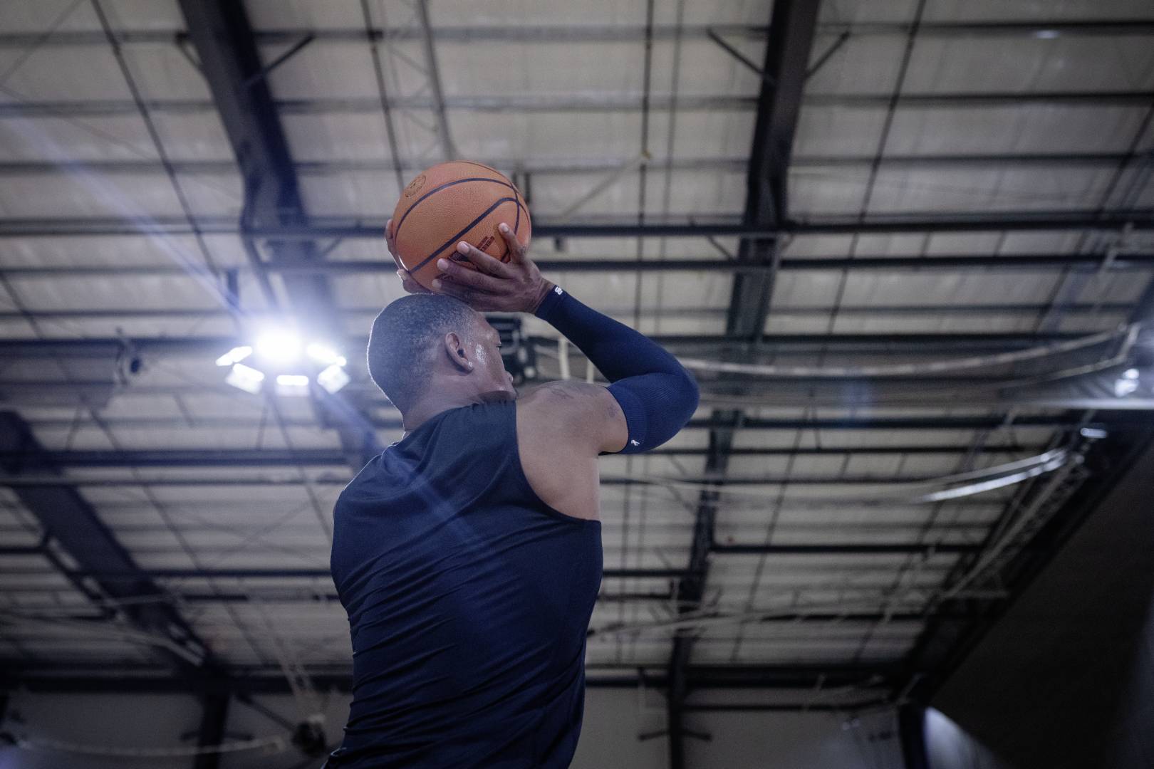 Basketball players with a blue armsleeve in a sports hall starts with their hands above the head to the throw