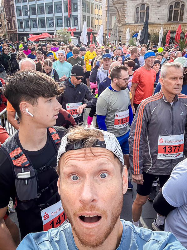 An excited participant takes a selfie just before the start of the 2024 Mitteldeutscher Marathon in Halle. Around him, many other runners are gathered, ready for the half marathon.