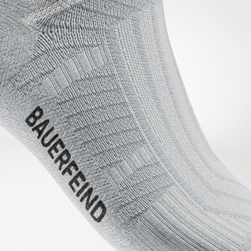 Side view of a white sports sock featuring a visible rib structure around the midfoot and a black “BAUERFEIND” logo – designed to support the arch while running.