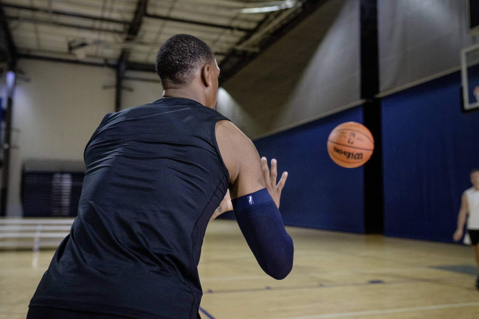 Basketball players with a blue Armsleeve in sports hall awaits a ball that is thrown at him by another player