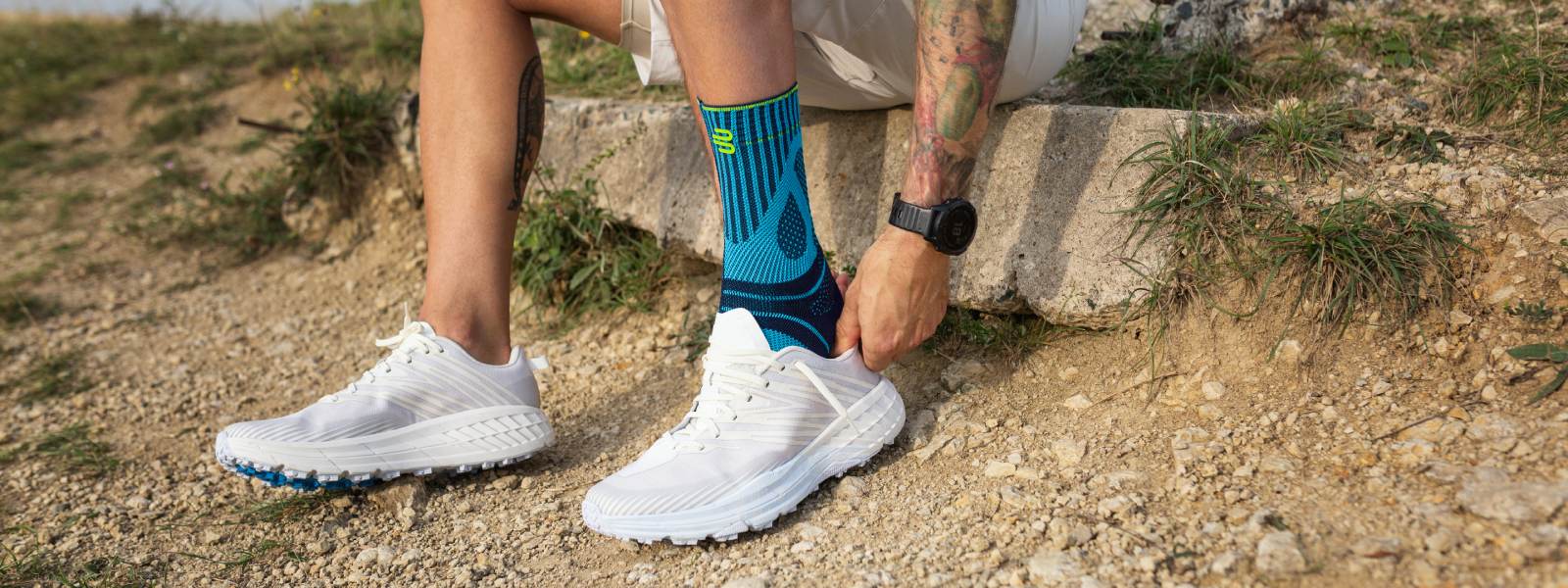 Man pulls a running shoe on a stone on a stone over his Achilles tendon bandage