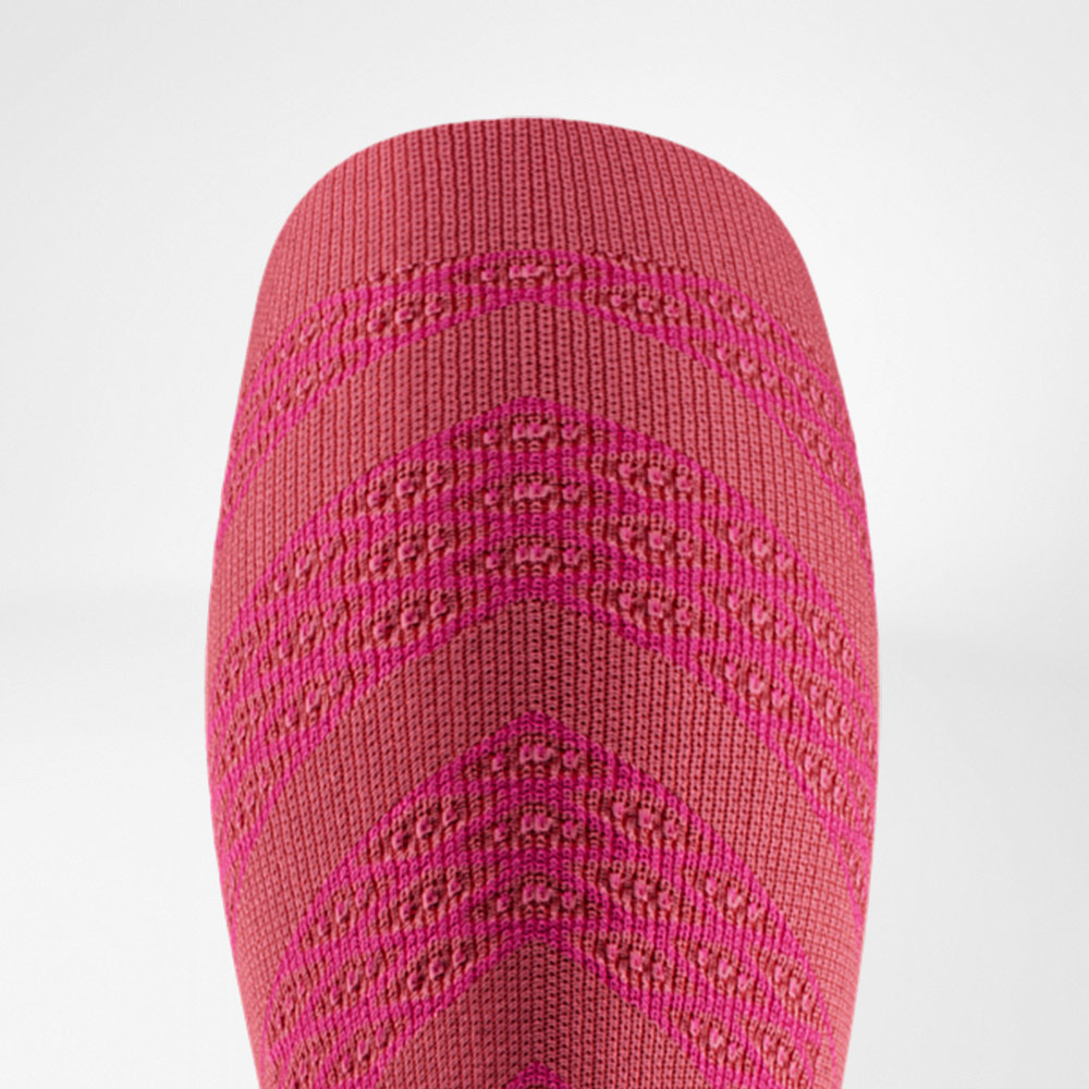 Close-up of a pink compression sleeve with fine knit structure and pattern, designed to support the calf muscles during running.