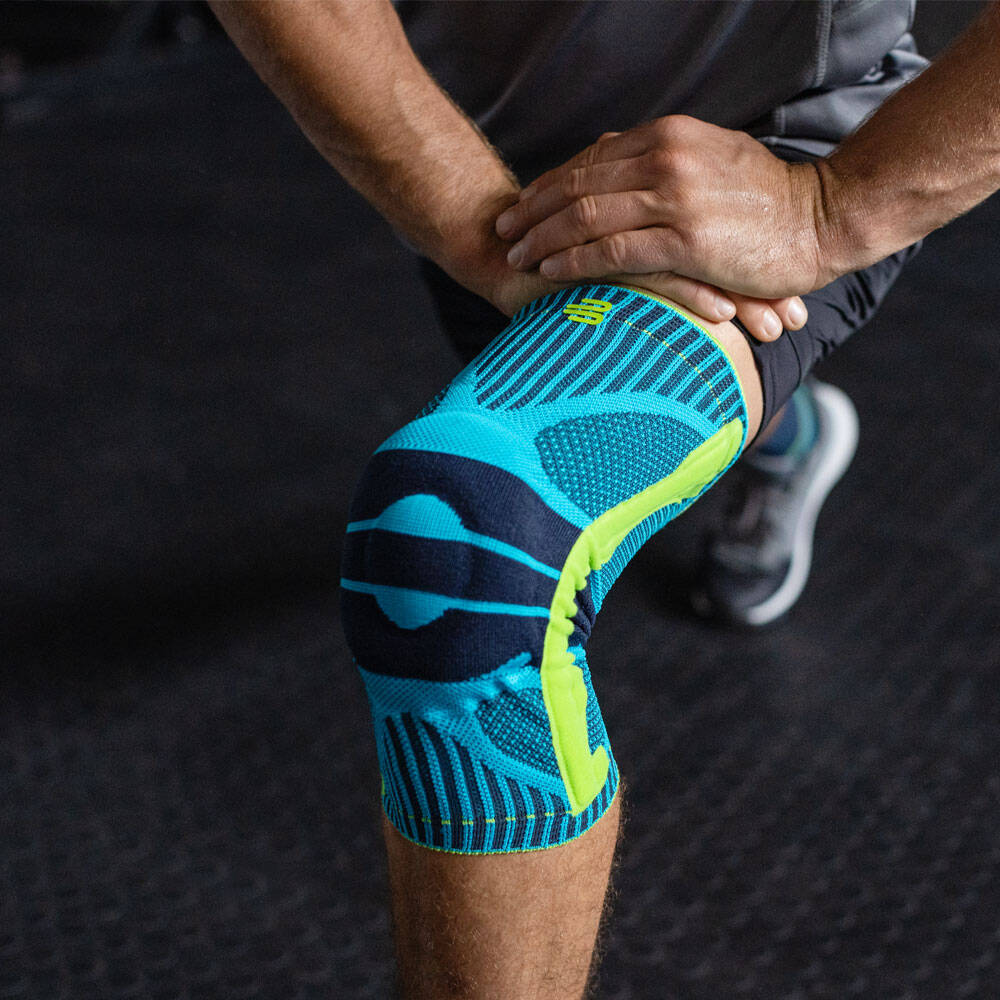 Man bends his knee and wears a sports knee support