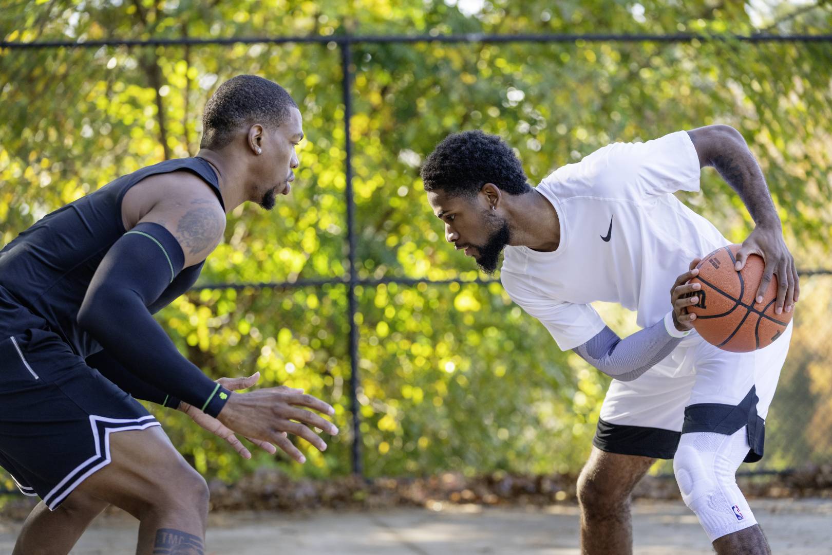 Streetball player in white game clothes tries to play his opponent in black game clothes