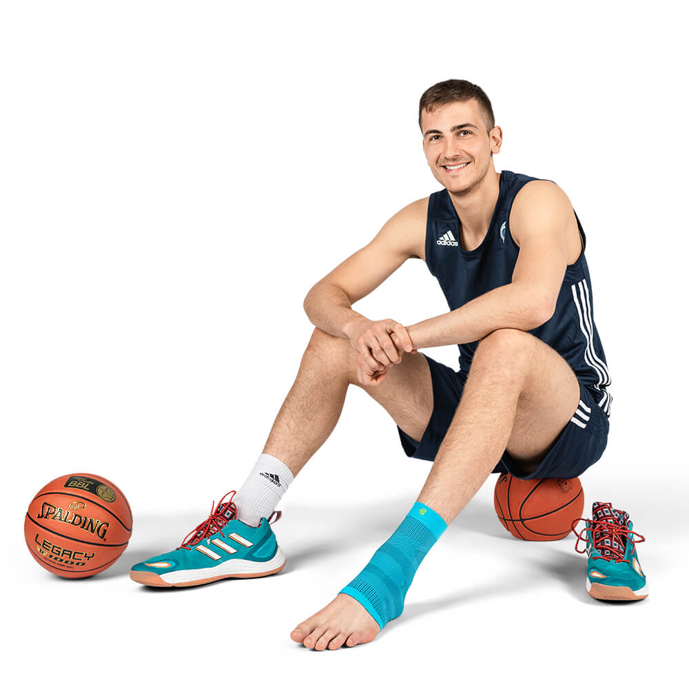 Fußleeve playing basketball Player sits on a basketball with Sleeve