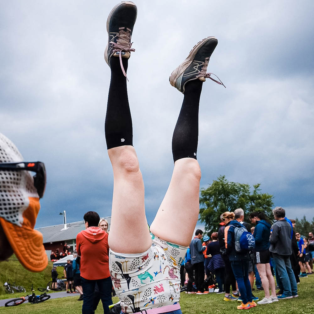 A woman in short sports shorts and knee-length stockings does a handstand