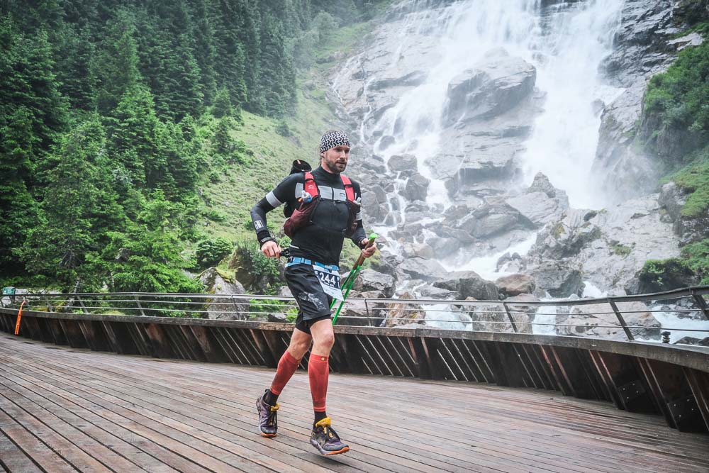 Lord Jens Kramer ultra running across a wooden bridge in front of a waterfall