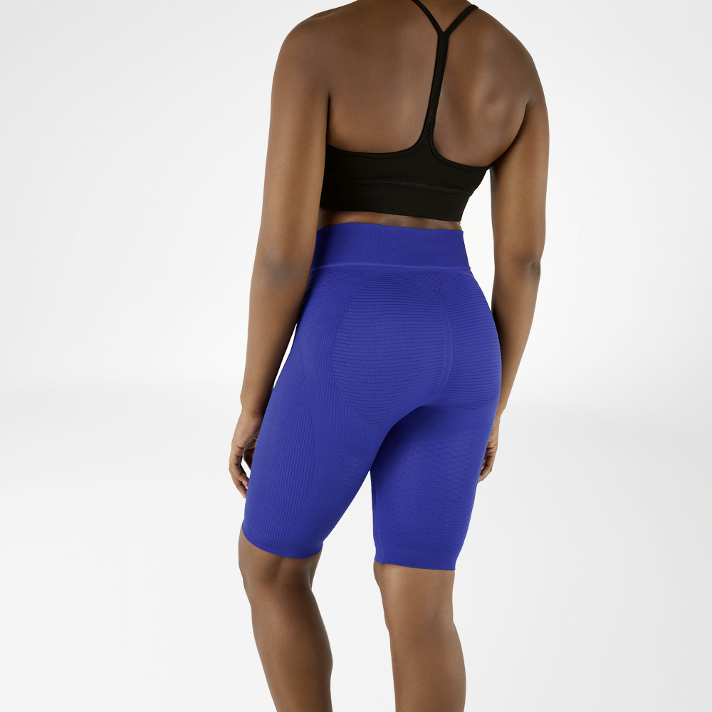 Woman photographed from behind in a black sports bra and knee-length, navy blue compression leggings.