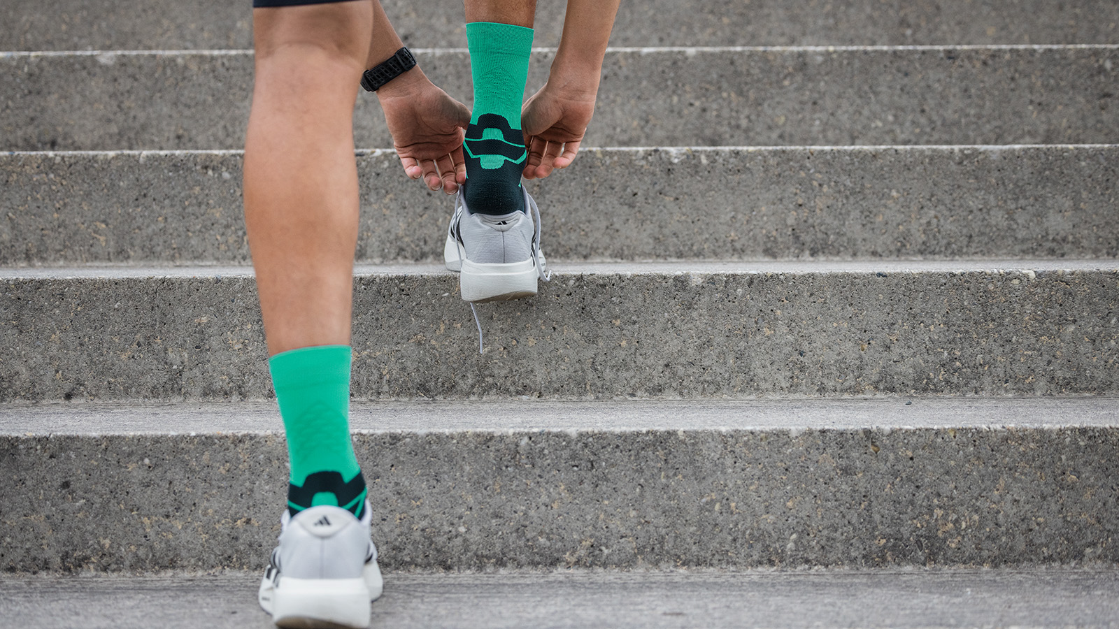 Just take off your running shoes and let your legs dangle a bit Man with blue and gray running socks sits on a fence and took off the shoes
