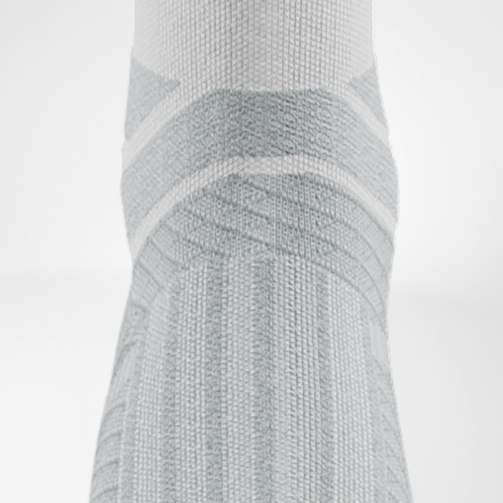 Close-up of the ankle area of the white Run Performance Socks, showing anatomical padding and supportive structures.