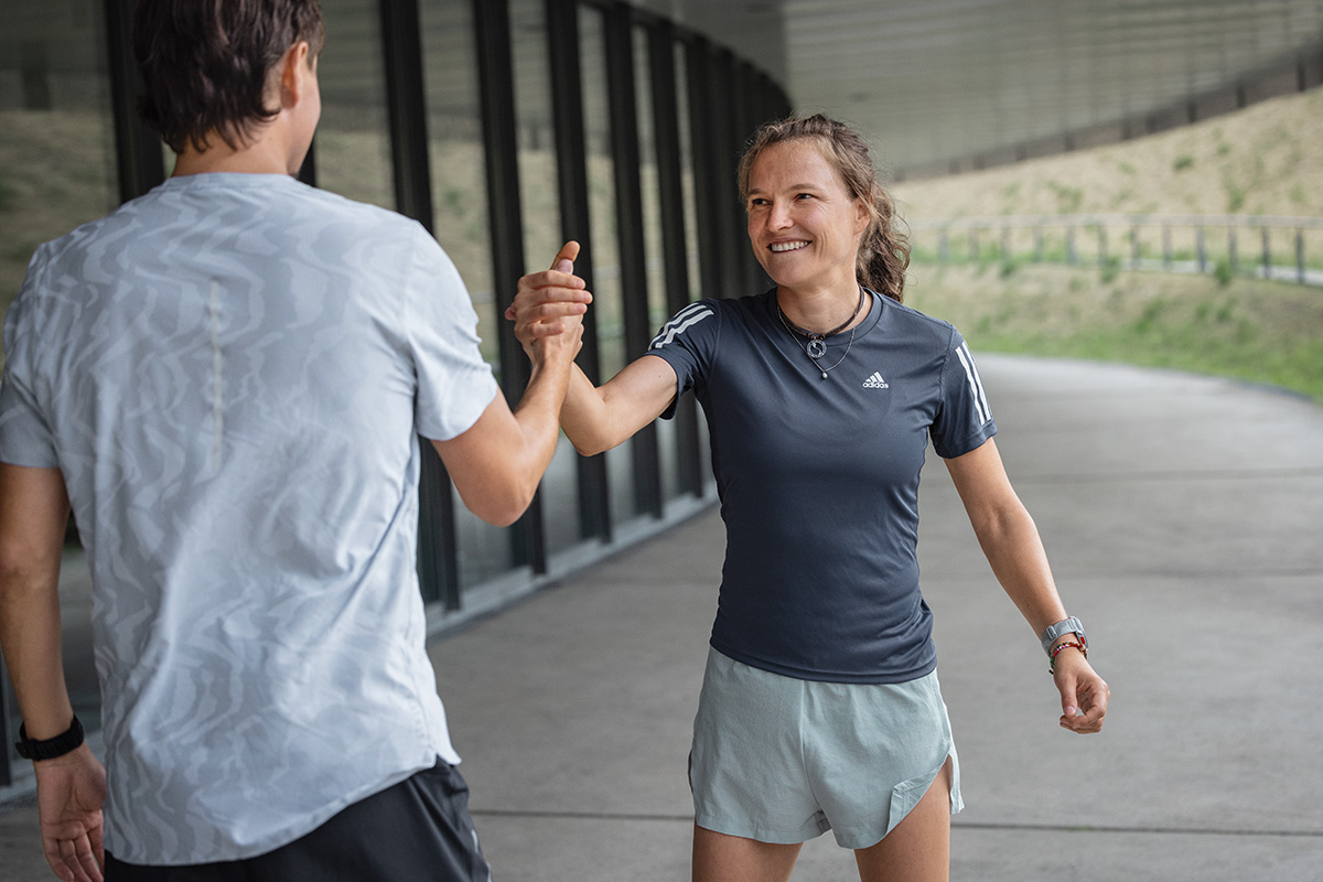 Woman in the summer running outfit sits on the floor and looks forward to the sunset