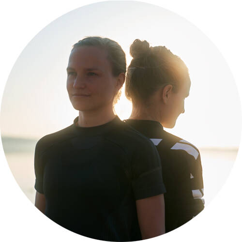 Long -distance runners Anna and Lisa stand back on back for a portrait of round image section