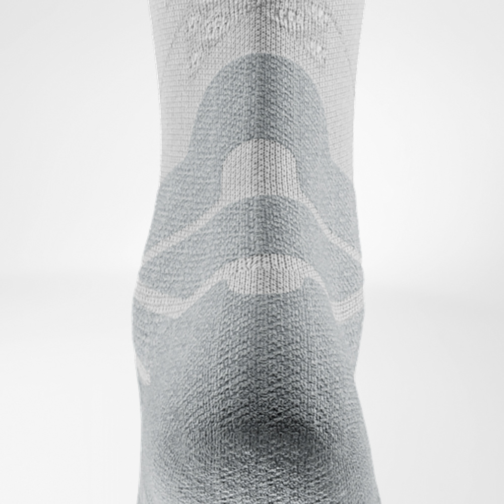 Detail view of the Achilles comfort pad on the white Run Performance Socks, designed to relieve pressure on the Achilles tendon.