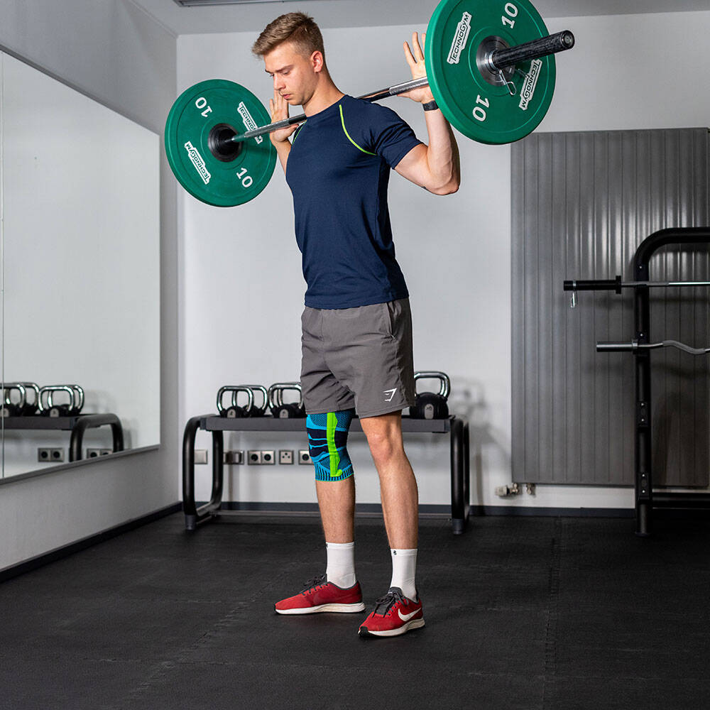 Man with a kneeze in gym is a barbell in his neck before executing a squat