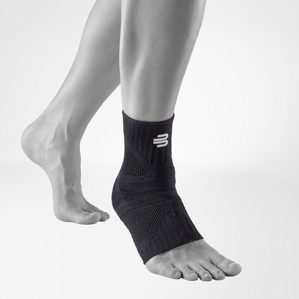 Ankle bandage Allblack front view diagonally Front complete view of the allblack-colored Ankle Support Dynamic on the stylized gray leg